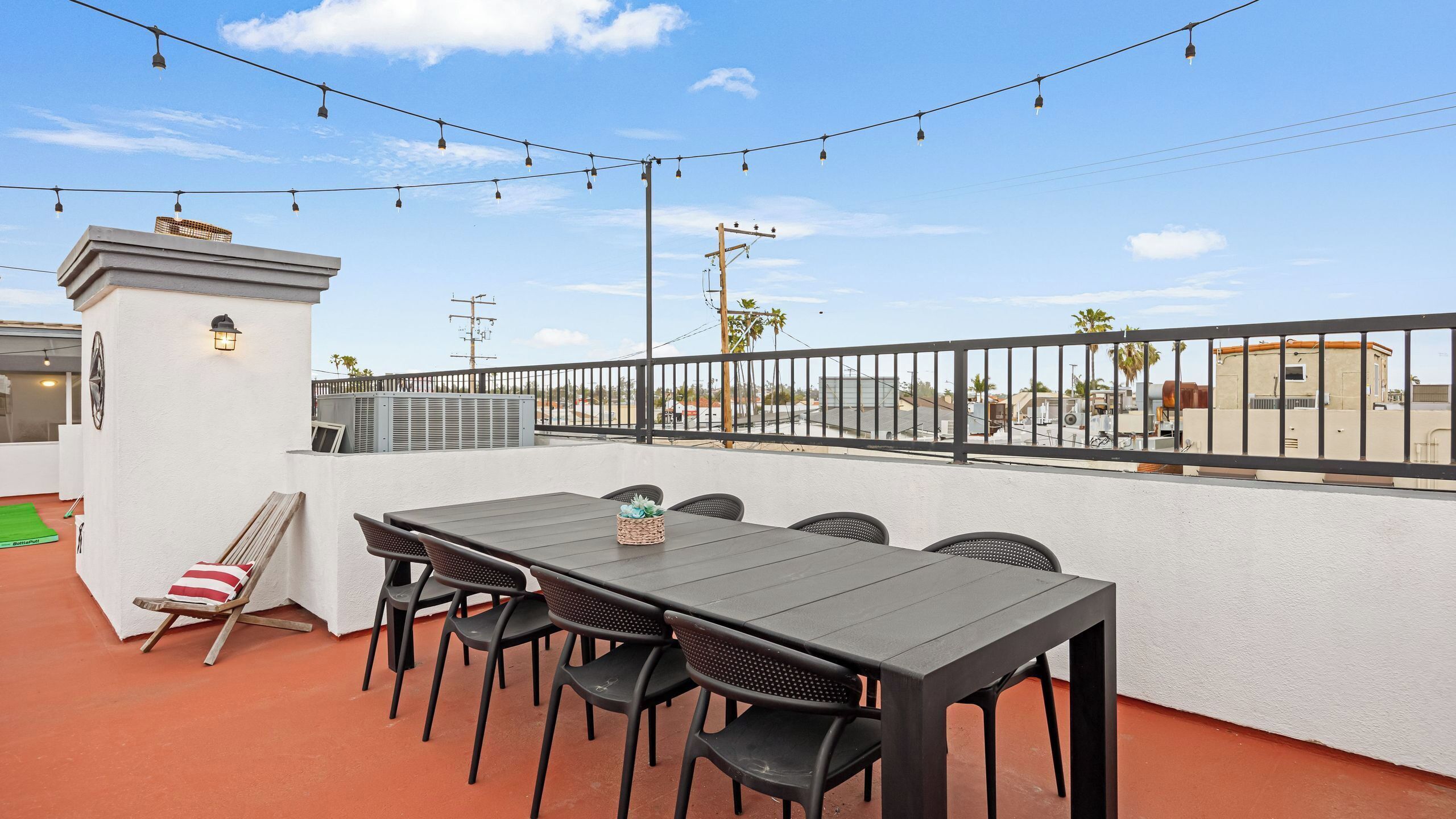 An outdoor patio with a table and chairs, string lights, and a view of the cityscape.