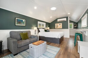 A cozy room with a gray sofa, a bed, a small table, and a wicker basket.