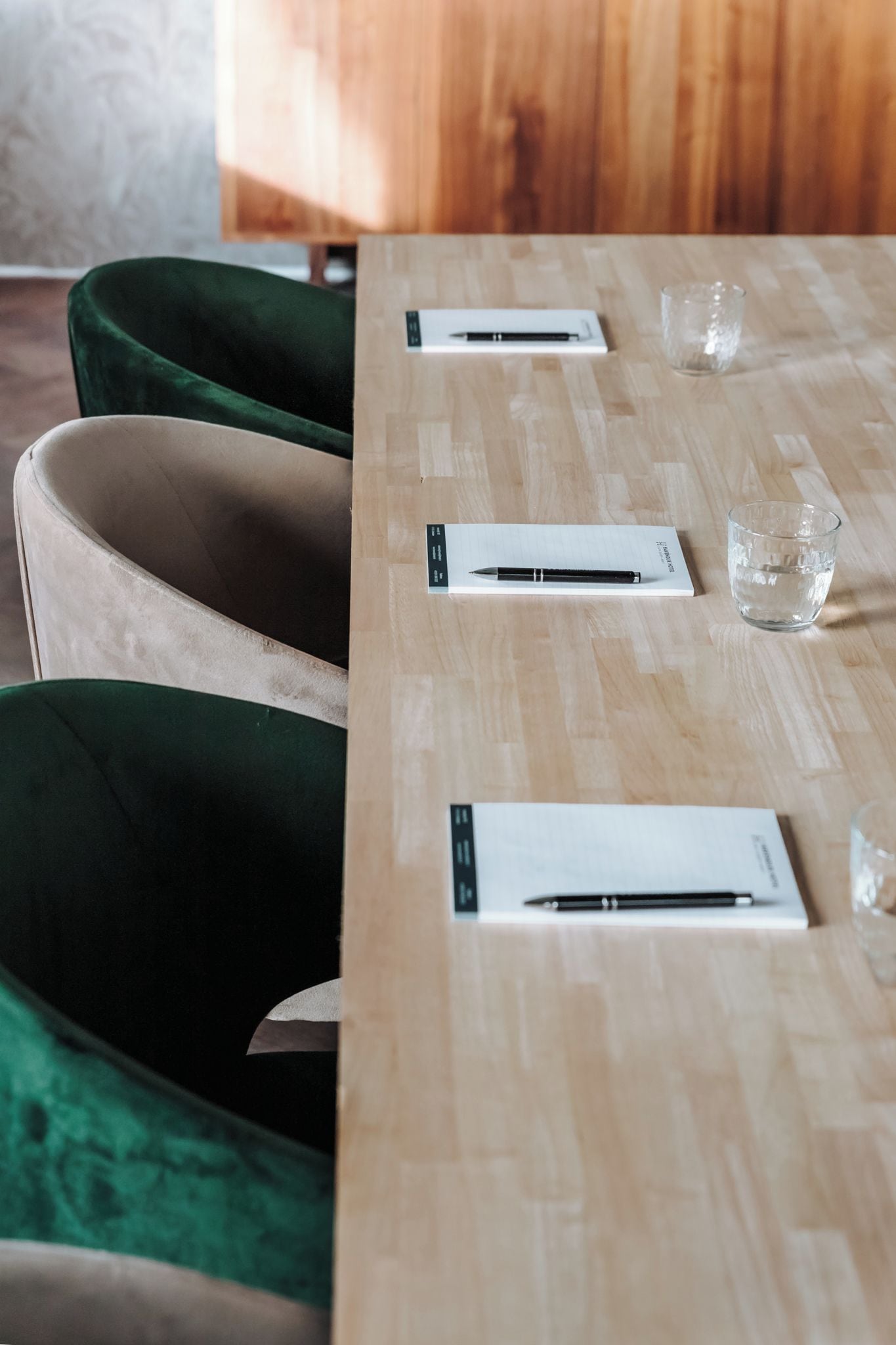 A wooden table with a pen and a glass of water on it.