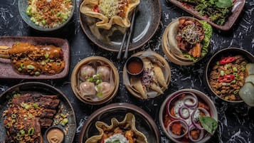 A variety of dishes including dumplings, a bowl of rice with green onions, and a plate of meat with sauce.