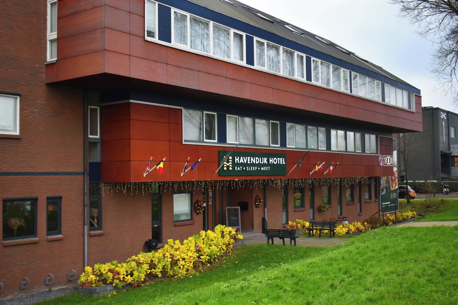 A hotel with a red facade, multiple windows, and a sign indicating it offers dining, sleeping, and meeting facilities.