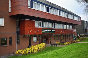 A hotel with a red facade, multiple windows, and a sign indicating it offers dining, sleeping, and meeting facilities.