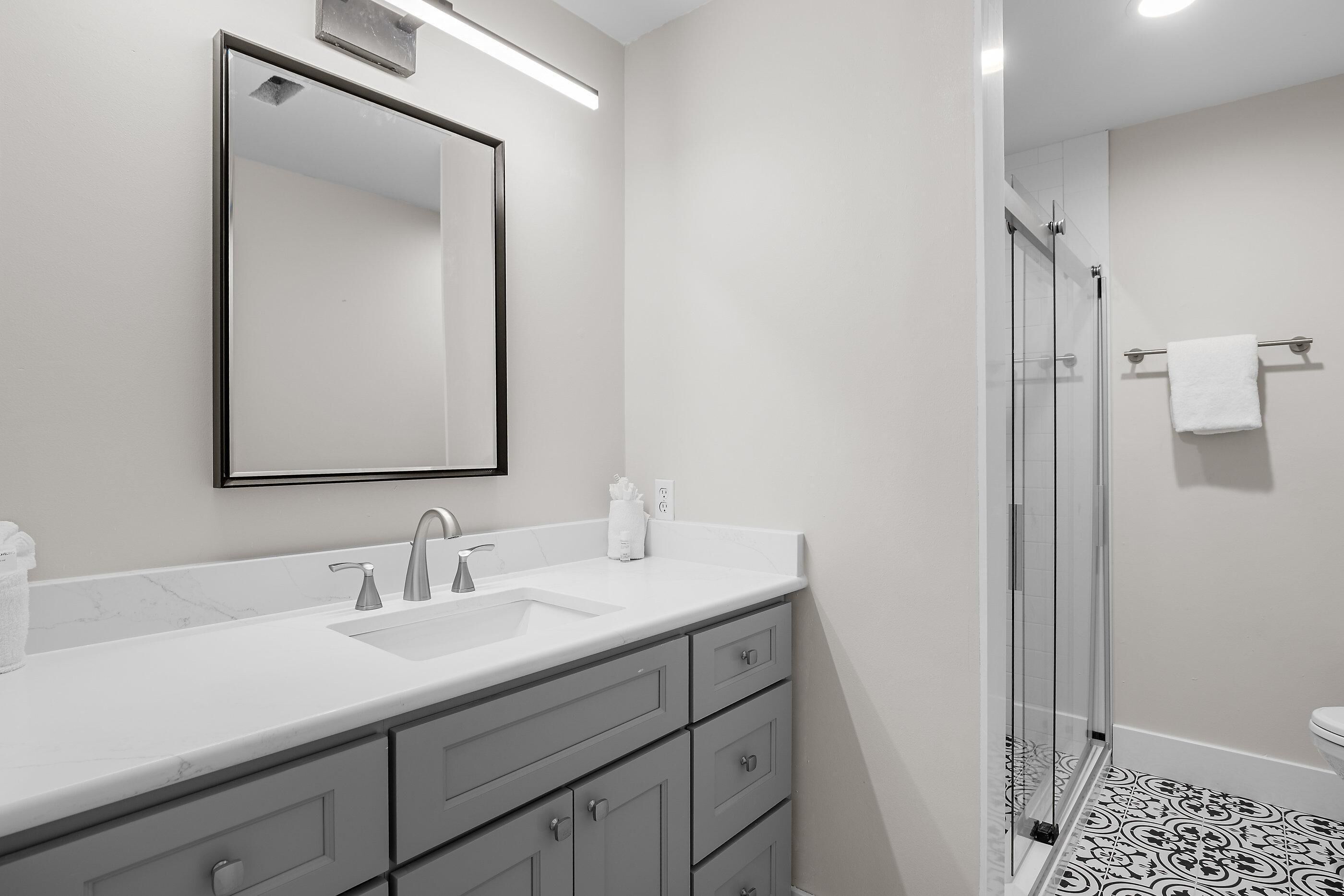 A modern bathroom with a double sink, a mirror, and a glass shower enclosure.