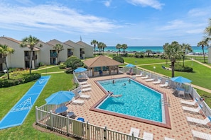 A pool area with a shuffleboard court, lounge chairs, and a view of the ocean. - Blue Surf 22 (Miramar Beach)