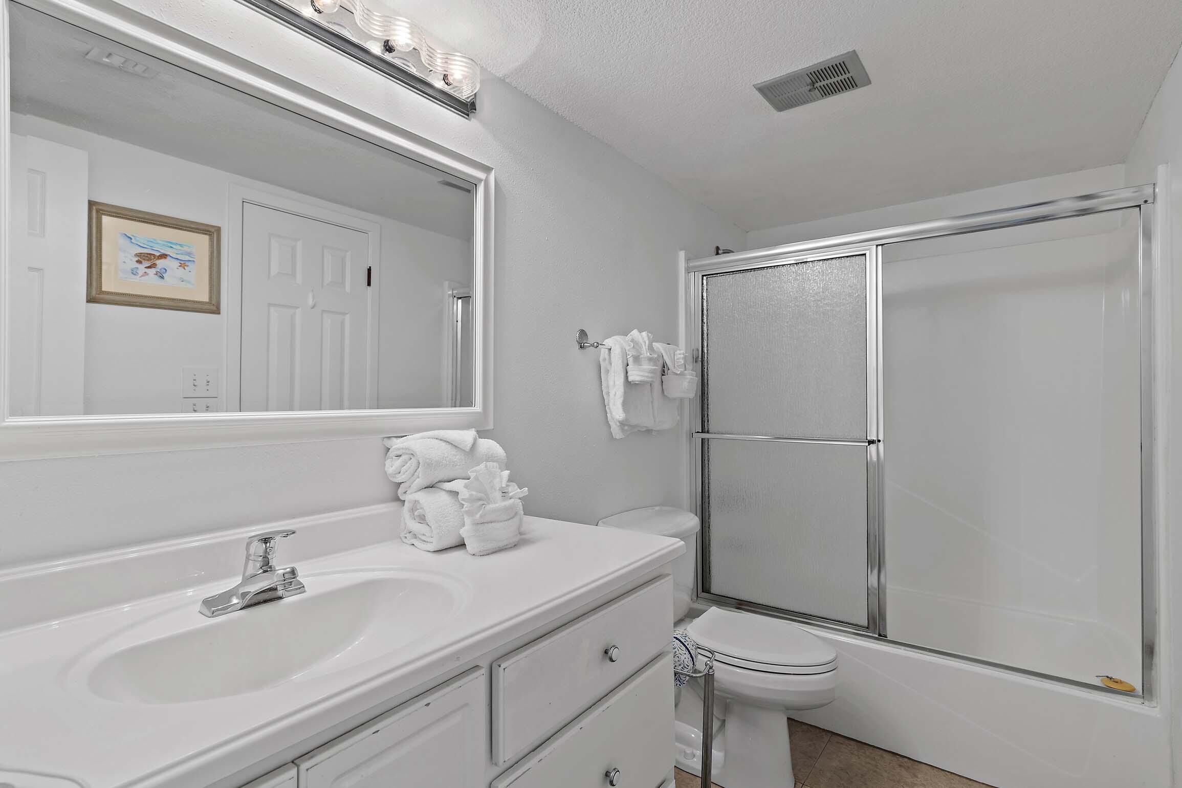 A bathroom with a white sink, mirror, and shower.