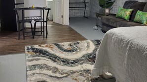 A bedroom with a bed, a desk, a chair, a small table, a potted plant, and a decorative wall piece. - Charming 1-bedroom apartment in amazing Wichita with WiFi, AC (Wichita)