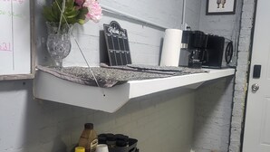 A kitchen counter with a coffee machine, a welcome sign, and a shelf with kitchen items. - Charming 1-bedroom apartment in amazing Wichita with WiFi, AC (Wichita)