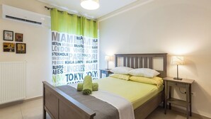 Ett hotellrum med en säng, ett sängbord, en lampa och en vägg med namn på olika städer.