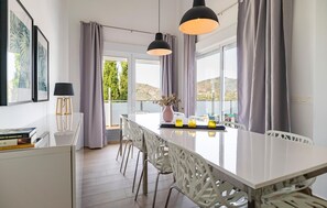 Eine moderne Küche mit einer großen Kochinsel, weißen Stühlen und Pendelleuchten.