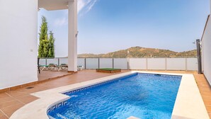 Une piscine avec vue sur les collines, un espace salon couvert et une pergola.
