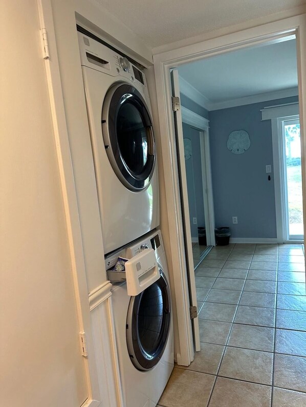A laundry room with two stacked front-loading washing machines and a dryer.