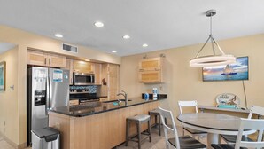 A modern kitchen with a central island, stainless steel appliances, and a dining area with a round table and chairs.