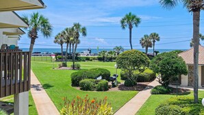 A well-maintained garden with palm trees, a pathway, and a view of the ocean. - Blue Surf 7 (Miramar Beach)