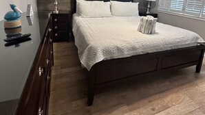 A bedroom with a wooden headboard, a bed with white bedding, two bedside lamps, a ceiling fan, and a window with blinds. - Blue Surf 7 (Miramar Beach)