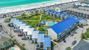 A hotel with multiple blue-roofed buildings, a swimming pool, and a beach view. - Blue Surf 7 (Miramar Beach)