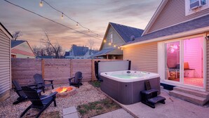 A backyard with a hot tub, outdoor seating, and string lights.