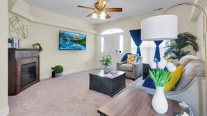 A living room with a fireplace, a ceiling fan, a flat-screen TV, a coffee table, and a sofa. - Minutes from Cherry Point (Havelock)