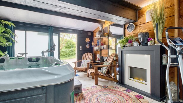A modern interior with a hot tub, wooden furniture, a fireplace, and a variety of decorative items.