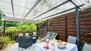 A covered patio with outdoor seating, a table set for breakfast, and a wooden fence in the background.