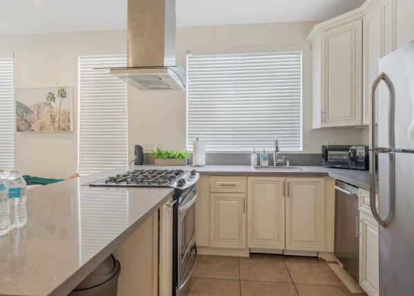 A modern kitchen with a central island, stainless steel appliances, and light-colored cabinetry.