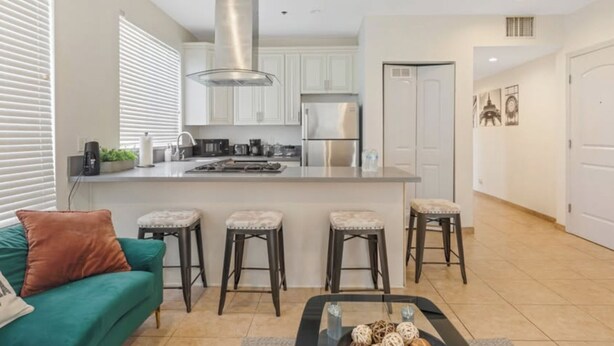 A modern kitchen with white cabinets, stainless steel appliances, and a central island with stools.
