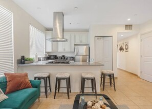 A modern kitchen with white cabinets, stainless steel appliances, and a central island with stools.
