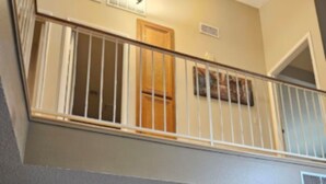 A room with a mounted flat-screen TV, a window with a wooden door, and a balcony with a white railing. - Charming 2-bedroom house in vibrant Las Vegas with WiFi, AC (Las Vegas)