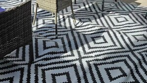 An outdoor patio area with wicker furniture, a glass table, and a patterned rug. - Charming 2-bedroom house in vibrant Las Vegas with WiFi, AC (Las Vegas)