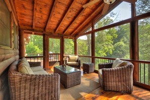A wooden deck with wicker furniture and large windows overlooking a forest. - Blue Ridge Creekfront Hot Tub Fishing and Tubing (Blue Ridge)