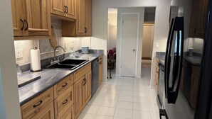 A modern kitchen with wooden cabinets, a stainless steel sink, and a built-in dishwasher.
