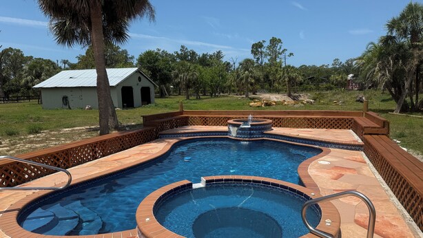 A swimming pool with a hot tub and a wooden deck.