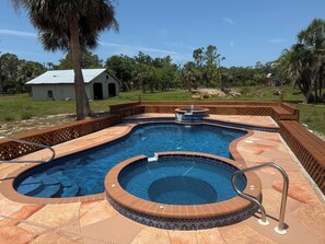 Una piscina con hidromasaje y un muelle de madera.
