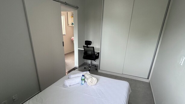 A hotel room with a bed, a desk, a chair, and a ceiling fan. - Comfort and practicality in the heart of Sorocaba (Jardim Santa Rosália Sorocaba)