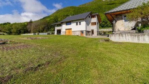 A modern two-story house with a large front yard and a mountain backdrop.