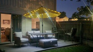 Un patio al aire libre con mobiliario de mimbre, una mesa y un paraguas amarillo.