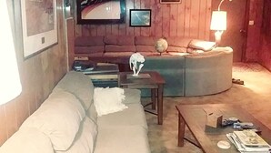 A cozy living room with a sofa, a small table, and a television mounted on the wall.