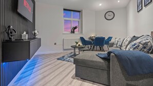 Una sala de estar moderna con un sofá gris, una mesa de centro y un televisor montado en la pared.
