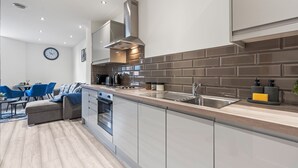 Una cocina moderna con una isla central, horno integrado y electrodomésticos de acero inoxidable.