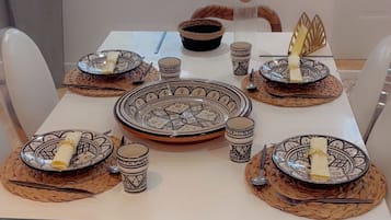 A dining table set with plates, bowls, and cutlery, surrounded by chairs.