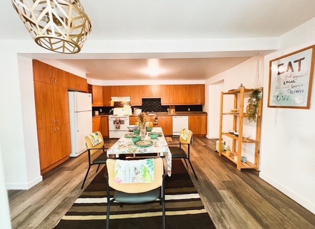 A modern kitchen with wooden cabinets, a dining table with chairs, and a kitchen island.