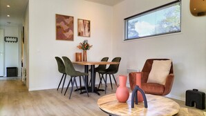A modern dining area with a wooden table, green and black chairs, and a round coffee table with vases. - 2 bedroom lovely home in Hellendoorn (Hellendoorn)