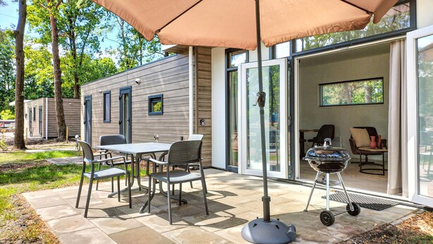A patio with a table and chairs, a barbecue grill, and an umbrella. - 2 bedroom lovely home in Hellendoorn (Hellendoorn)