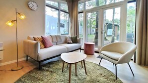 A modern living room with a sofa, a small table, a chair, and a floor lamp. - Awesome home in Hellendoorn with WiFi (Hellendoorn)