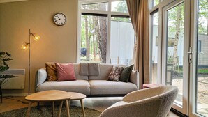 A cozy living room with a sofa, two armchairs, a coffee table, a floor lamp, and a large window with curtains. - Awesome home in Hellendoorn with WiFi (Hellendoorn)