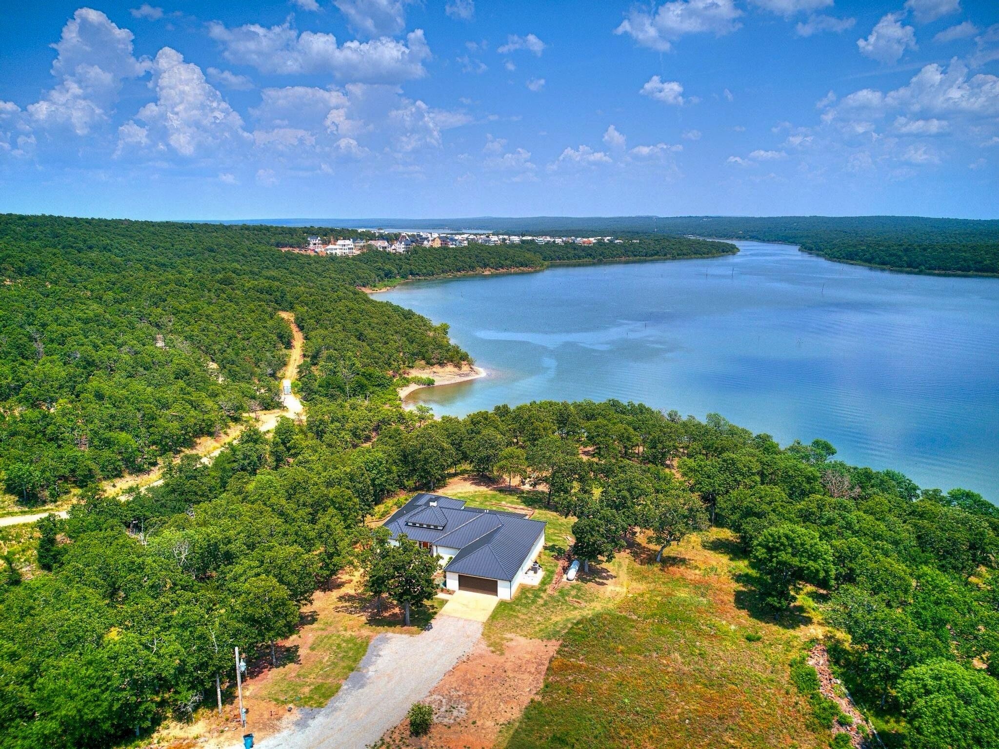 Une maison avec un garage, entourée d’une forêt dense et d’un lac.