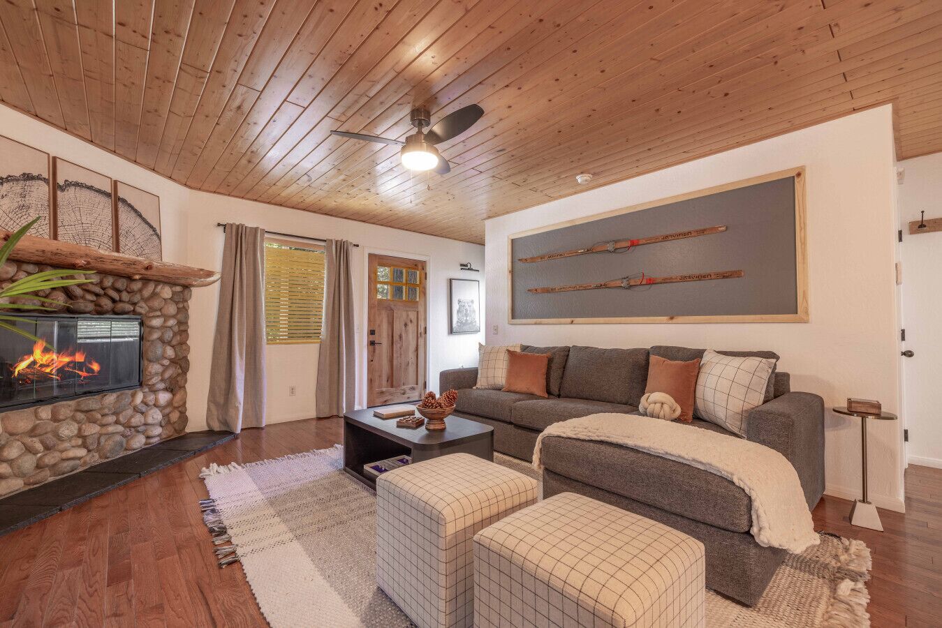 A cozy living room with a stone fireplace, wooden ceiling, and a large sofa.