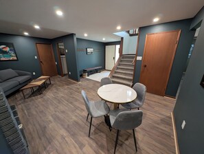 Un salon moderne avec un canapé, une table basse et une table à manger avec des chaises. Un escalier mène à un autre niveau.