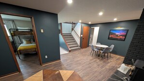 A modern living room with a wooden coffee table, a fireplace, and a dining area with chairs.