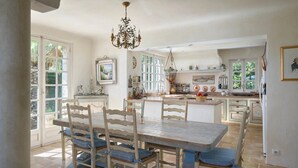 Una cocina amplia con una isla grande, muebles blancos y una araña.