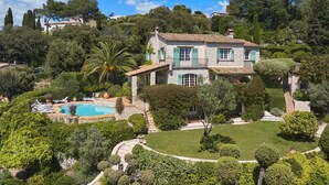 Una amplia casa de piedra con piscina, rodeada de exuberante vegetación y árboles.
